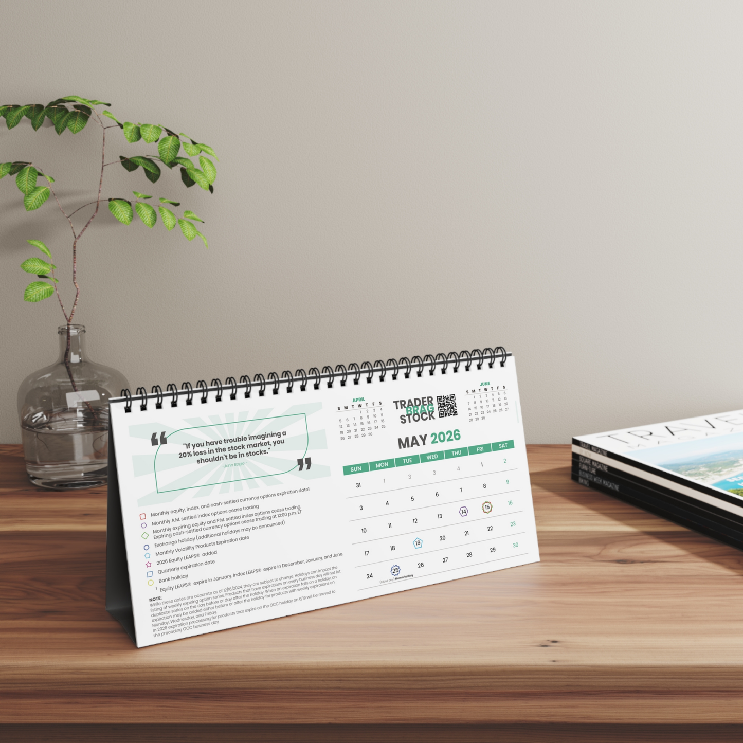 Tabletop trader calendar on a wooden surface with a plant and book in the background