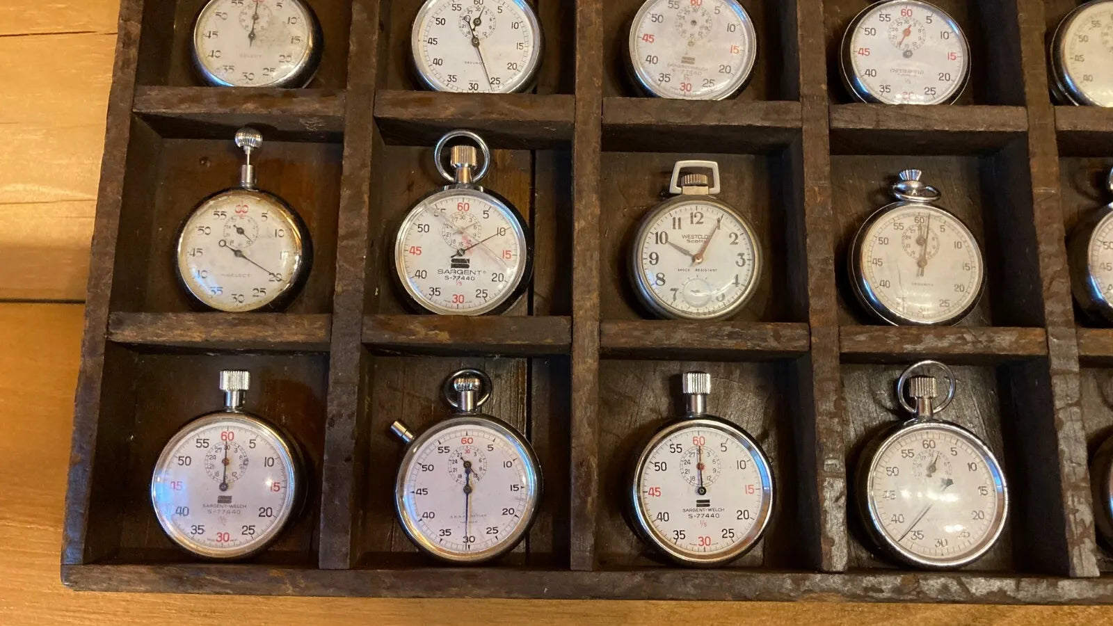 Assortment of vintage stopwatches and pocket watches mounted on a wall display, ideal for restaurant, man cave, or home decor, showcasing a range of designs and eras.