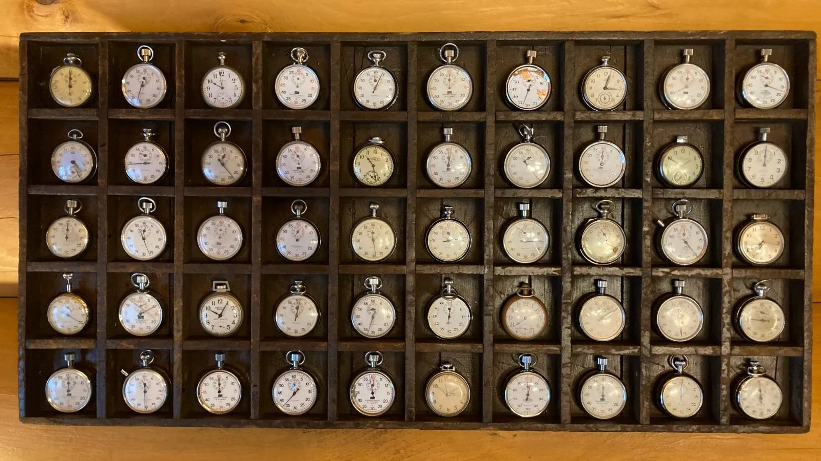 Assortment of vintage stopwatches and pocket watches mounted on a wall display, ideal for restaurant, man cave, or home decor, showcasing a range of designs and eras.